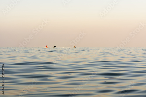 Fotografie, Tablou evening sea with waves, far away on a horizon line floating water bike, nature a