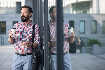 Wall Mural - Positive male office worker leaning on glass wall