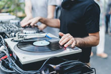 DJ Mixing Vinyl Records On A Turntable In A Daily Outdoor Party. Focus On His Hands