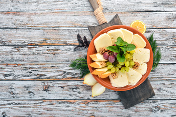 Cheese on a plate. Brynza and Suluguni cheese. On the old wooden background. Free space for text. Top view.