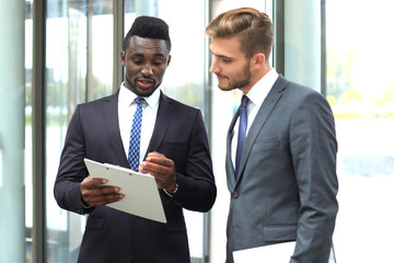 Two multinational young businessmen discussing business at meeting in office.