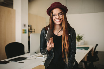 Wall Mural - Women entrepreneur standing in office holding a tablet pc