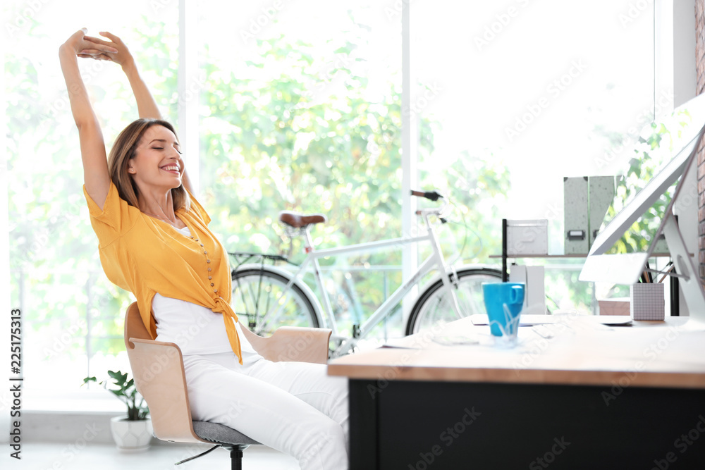 Beautiful young businesswoman stretching in office. Workplace fitness - obrazy, fototapety, plakaty 