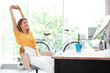Beautiful young businesswoman stretching in office. Workplace fitness