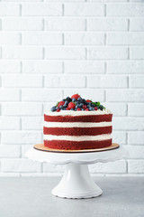 Stand with delicious homemade red velvet cake near brick wall