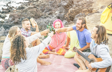 Wall Mural - Group of happy friends toasting beers and playing guitar camping with tent on the beach - Travel people having fun listening music and drinking alcohol outdoor - Vacation, youth lifestyle concept