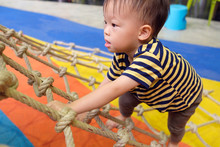Cute Little Asian 2 Years Old Toddler Baby Boy Child Having Fun Trying To Climb On Jungle Gym At Indoor Playground, Physical, Hand And Eye Coordination, Sensory, Motor Skills Development Concept
