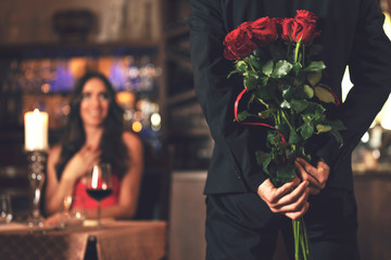 romantic surprise concept - a man holding a bouquet of roses and wants to give it to a woman during 