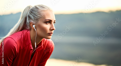 Beautiful young woman having rest and listening music outdoors during morning ru Obraz na płótnie