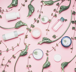 Wall Mural - modern cosmetic flat lay with bottles and facial cream, plants and flowers on pink background. skin 
