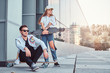 © Fxquadro - Trendy dressed couple - young hipster man sitting on a longboard and his girlfriend standing near outdoors.