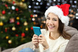 © Antonioguillem - Woman holding smart phone looking at camera in christmas