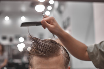 Close-up, master Barber does the hairstyle and styling with dryer, dries hair to guy. Concept Barbershop. Soft focus.