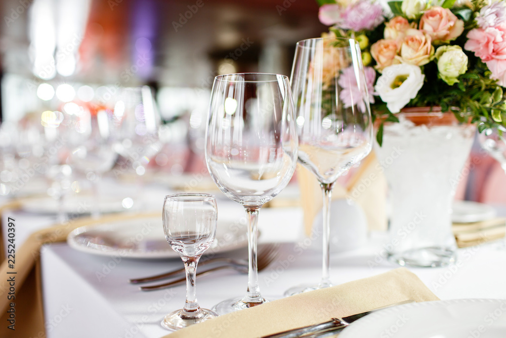 Table at a luxury wedding reception. Beautiful flowers on the table. Serving dishes, glass glasses, waiters work,