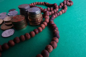 Wall Mural - Islamic Banking/Financing Conceptual with rosary and coins on a green background.