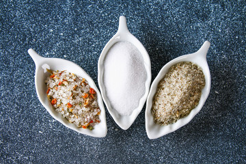 Wall Mural - Different types of salt in glass bowls on a dark gray table.