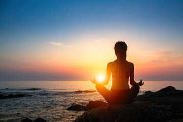 Meditation girl on the sea during sunset. Yoga silhouette.