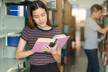 Canvas Print - Student learning in library. Young girl read book in library for doing research assignment.