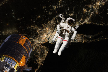 Wall Mural - astronaut flying in open space over the usa during night, near earth. image made of nasa photos f