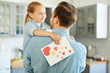 © pressmaster - Little girl with greeting card looking at her dad while listening to what he is saying