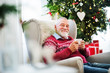 © Halfpoint - A portrait of senior man with a cup sitting on armchair at home at Christmas time.