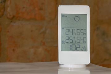 Wall Mural - Home weather station device with weather conditions inside and outside on a brick background.