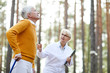 © pressmaster - Rehabilitation specialist in glasses supporting senior patient and talking to him while they walking in forest, motivated senior man learning to walk after trauma