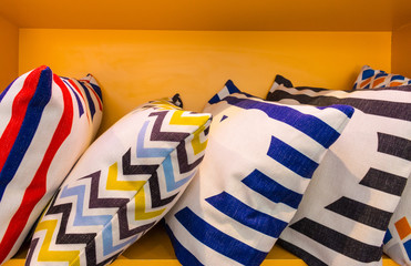 Poster - Colorful pillow and design pattern on yellow shelf. Modern cushions and interior furniture.