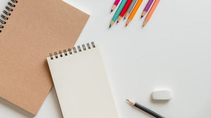 Wall Mural - open blank spiral notebook with pencil, eraser and color pencil on white background.