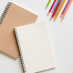 Wall Mural - open blank spiral notebook with pencil, eraser and color pencil on white background.
