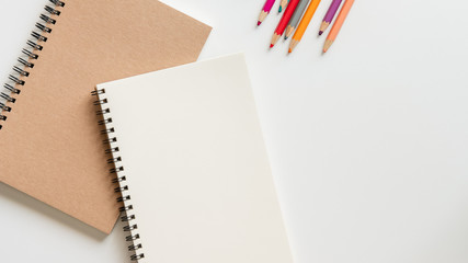 Wall Mural - open blank spiral notebook with pencil, eraser and color pencil on white background.