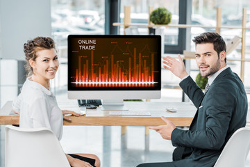 Wall Mural - smiling business colleagues at workplace with computer screen with online trade lettering in office