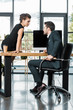 © LIGHTFIELD STUDIOS - young business colleagues flirting at workplace with blank computer screen in office