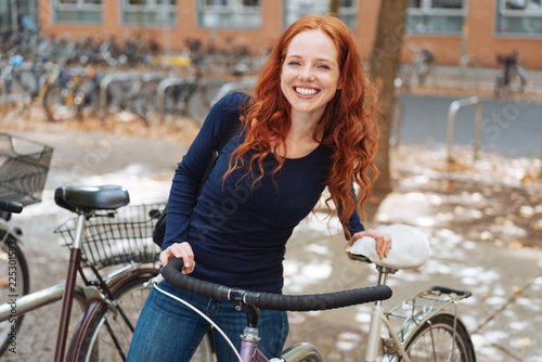 Fototapeta na szkło Uśmiechnięty szczęśliwy młody uczeń z jej bicyklem