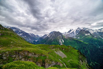 Wall Mural - Scenic view of beautiful landscape in Swiss Alps. Fresh green meadows and snow-capped mountain tops in the background in springtime, Switzerland.