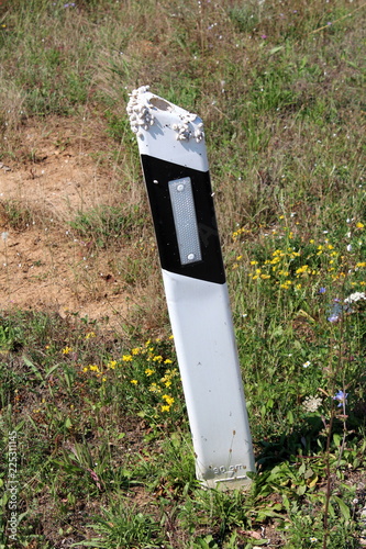 Fotografía Leaning black and white plastic roadside pole with reflective patch covered on t
