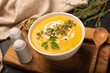 Pumpkin cream soup in bowl decorated with cream, pumpkin seeds and thyme. Selective focus