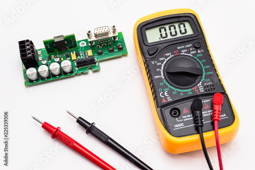 Fotografie, Obraz Electric multimeter with red and black probe, display indicating zero, with printed circuit board