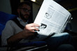Close up of unrecognizable man holding business newspaper  while reading in plane, shot with flash, copy space