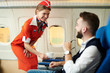 © Seventyfour - Portrait of smiling flight attendant serving coffee to young businessman in first class, copy space