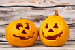 © DenisProduction.com - Funny Halloween pumpkins on wooden background. Two smiling Jack-O-Lantern pumpkins. Symbols of Halloween holiday.