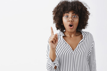 Wall Mural - smart and creative artistic african american in striped office blouse and glasses raising index fing