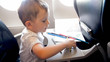 Portrait of little toddler boy holding pencils flying in airplane
