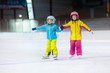 Children skating on ice rink. Kids winter sport.