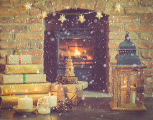 Wall Mural - Christmas composition, lantern, presents and decorations on the table in front of fireplace with woodburner, Christmas tree with baubles and ornaments and garlands, snow, selective focus, toned