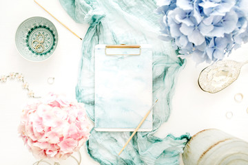 Wall Mural - Artist home office desk workspace with watercolor clipboard, paintbrush, turquoise blanket, colorful pastel hydrangea flower bouquet, woman fashion accessories on white background. Flat lay.