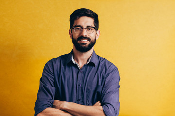 Poster - Portrait of a smiling bearded man in eyeglasses looking at camera isolated over yellow background