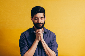 Poster - Portrait of a bearded man praying isolated over yellow background