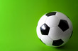 © Victor Moussa - Sports equipment and leisure activity concept with a black and white generic classic leather football or soccer ball isolated on green background with copy space