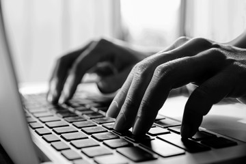 Black and white colour.Close up fingers typing on the computer keyboard,pressing buttons, typing,
